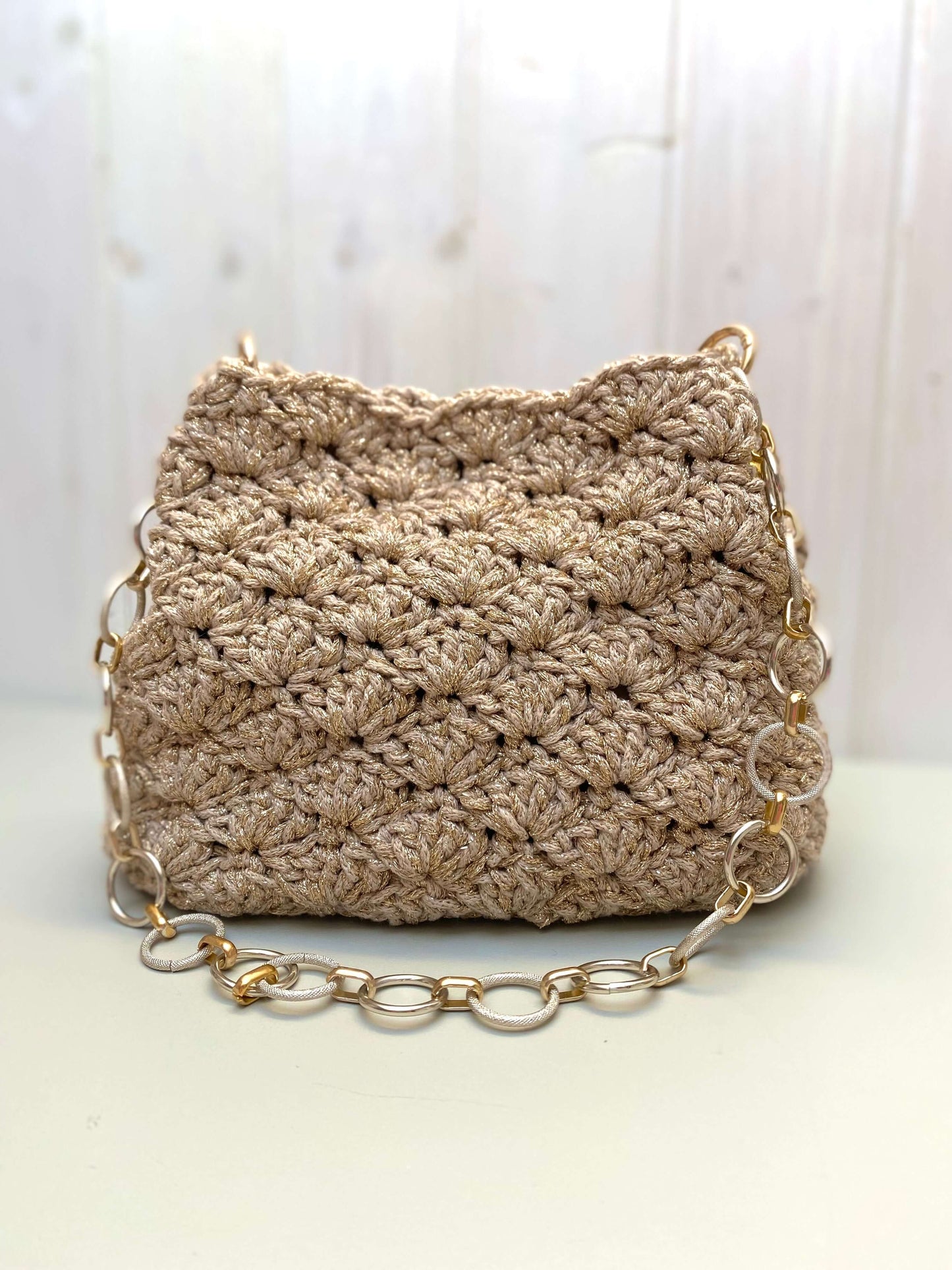Borsa uncinetto Kira beige dorato piccola con dettagli in oro e manico a catena.